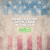 Handcrafted Glow Products Made in USA - Just Keep Glowing. American flag inspired design with text 'Handcrafted With Care In The USA.'  Glow-in-the-dark items made with attention to detail.  Support local craftsmanship in North Carolina.  High-quality, handcrafted glow products.  Patriotic design for American-made goods.  Unique, handcrafted glow items from Just Keep Glowing.