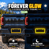 Amber yellow license plate frame shown on a black pickup truck in daylight and glowing amber yellow at night.