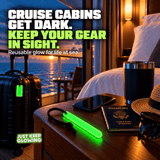 Forever Glow Stick glowing on a cruise cabin nightstand beside a passport, with a reusable green glow tag attached to luggage, showing battery free travel accessories for cruise vacations.