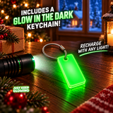 Reusable green glow in the dark keychain included with the Elf Farts Christmas gift, featuring a stainless steel cable loop and illuminated by a flashlight on a festive wooden table.