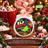 Elf Farts scented Christmas jar with its illustrated lid leaning against it, surrounded by hot cocoa, peppermint candies, marshmallows and chocolate with magical fragrance effects.