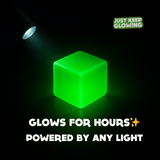 Green glow in the dark resin cube charging under a flashlight – eco-friendly sensory fidget toy powered by any light