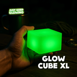 Glow Cube XL rechargeable glow-in-the-dark night light glowing on a table, handmade in the USA.