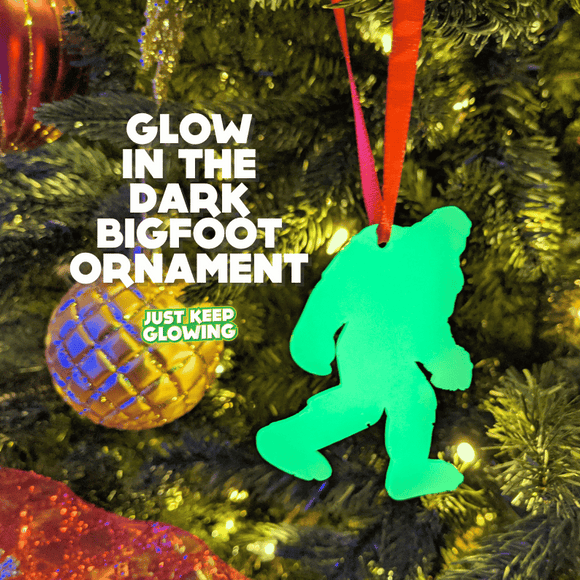 Glow-in-the-dark Bigfoot Christmas ornament hanging on a festive tree, emitting a bright green light.