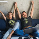 Couple wearing glow in the dark Bigfoot shirts relaxing on couch showcasing glowing print