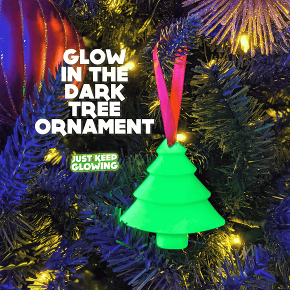 Close-up of a glowing green glow-in-the-dark Christmas tree ornament hanging on a decorated tree, highlighting its unique luminescence. 'Glow in the Dark Tree Ornament' text overlay.