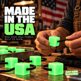 Hands assembling handmade green Mini Glow Cubes with black paracord on a workshop table, with a Made in the USA message and American flag.
