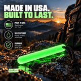 Waterproof Forever Glow Stick glowing green on wet rocks beside a hiking backpack at sunrise, highlighting durable American made reusable glow gear.