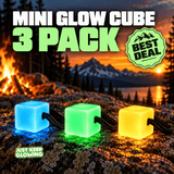 Mini Glow Cube three pack with green, aqua blue and amber yellow glowing cubes, each with its own black paracord loop, displayed at a mountain campsite.