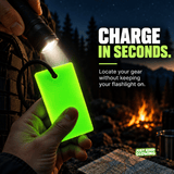 Forever Glow Bar illuminated by a handheld flashlight at a dark campsite, showing how reusable glow gear charges in seconds to help locate emergency supplies without keeping a flashlight on.