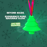 Glowing green Christmas tree ornament with red ribbon, showcasing its pure, reusable, and battery-free glow against a festive snowflake background. 'Beyond Bulbs. Experience Pure, Reusable Glow' text.